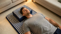 Man relaxing on the Restveta acupressure mat with the neck bolster